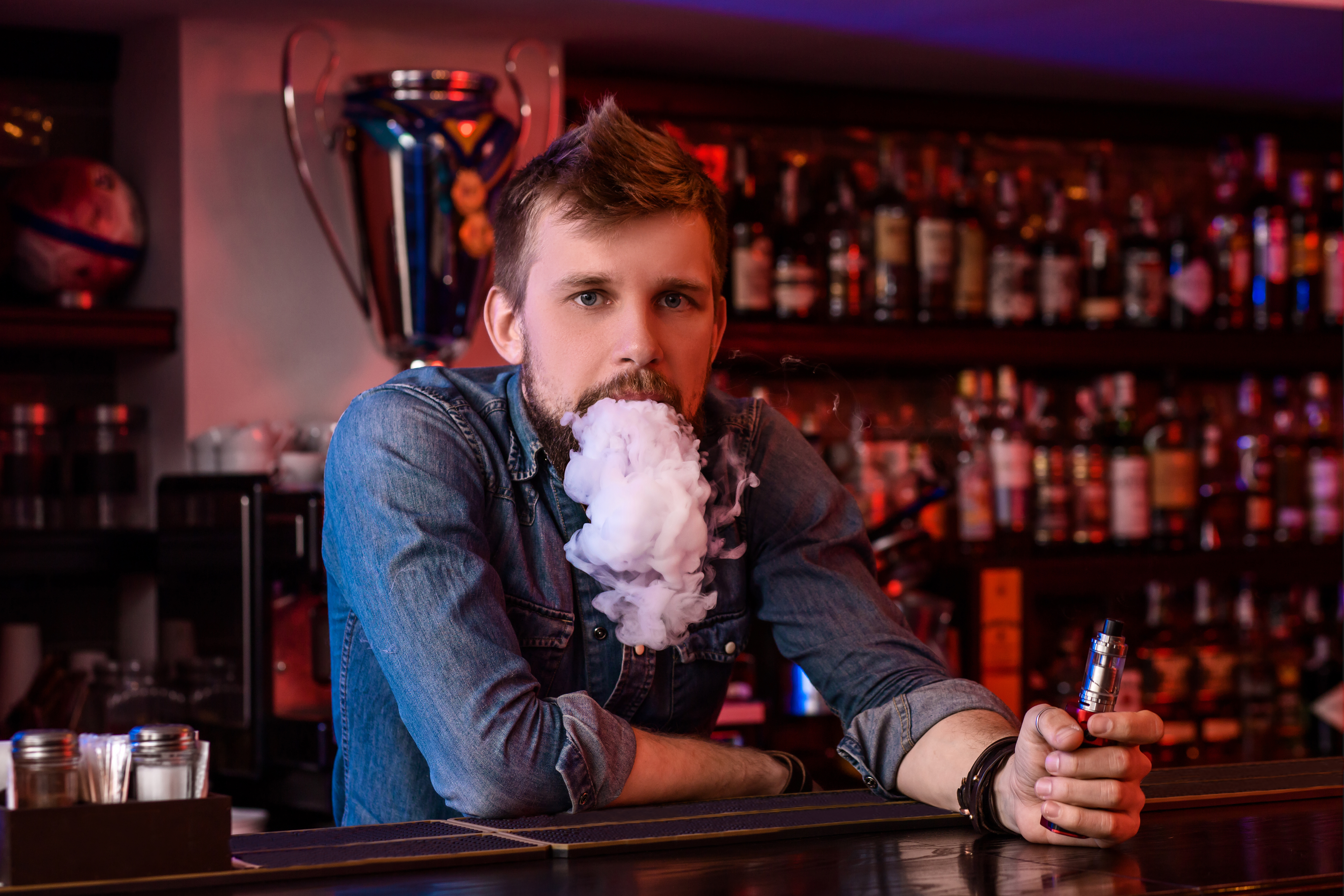 Vape. Vaping man in a cloud of vapor. Photo is taken in a vape bar. Vape shop